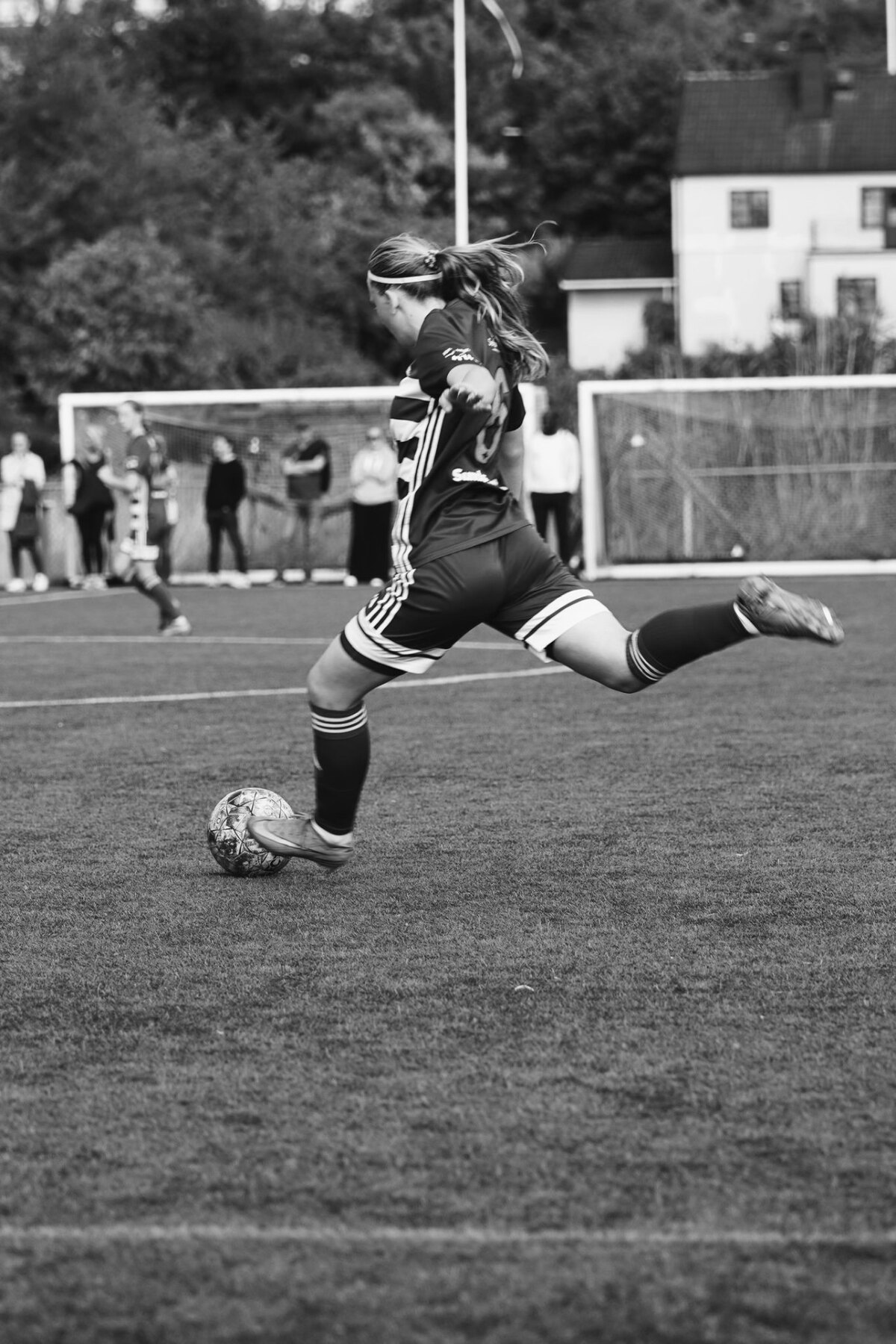 Ung fotbollsspelare sparkar bollen på planen
